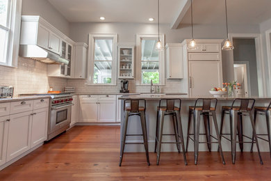 Inspiration for a l-shaped medium tone wood floor eat-in kitchen remodel in Atlanta with a farmhouse sink, shaker cabinets, white cabinets, quartzite countertops, white backsplash, ceramic backsplash, stainless steel appliances and an island