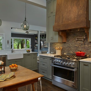 Inspiration for a mid-sized country u-shaped open plan kitchen in Atlanta with a farmhouse sink, shaker cabinets, green cabinets, brown splashback, ceramic splashback, panelled appliances, medium hardwood floors, with island and brown floor.