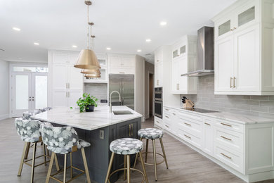Kitchen - transitional l-shaped gray floor kitchen idea in Miami with an undermount sink, recessed-panel cabinets, white cabinets, gray backsplash, subway tile backsplash, stainless steel appliances, an island and white countertops