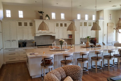 Large transitional l-shaped dark wood floor and brown floor eat-in kitchen photo in Orange County with recessed-panel cabinets, white cabinets, granite countertops, paneled appliances, an island and gray backsplash