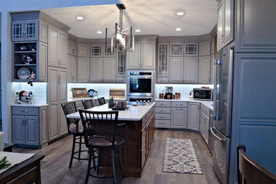 U-shaped brown floor eat-in kitchen photo in Other with a double-bowl sink, raised-panel cabinets, gray cabinets, marble countertops, white backsplash, stainless steel appliances, an island and white countertops