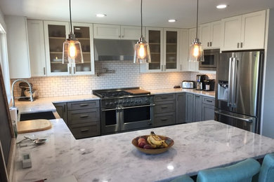 Inspiration for a mid-sized industrial u-shaped dark wood floor eat-in kitchen remodel in Seattle with a farmhouse sink, recessed-panel cabinets, gray cabinets, marble countertops, white backsplash, subway tile backsplash, stainless steel appliances and no island