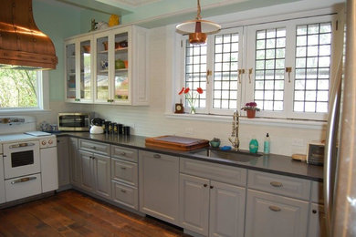 Inspiration for a mid-sized country u-shaped medium tone wood floor and brown floor eat-in kitchen remodel in New York with an undermount sink, raised-panel cabinets, gray cabinets, granite countertops, white backsplash, subway tile backsplash, stainless steel appliances and a peninsula