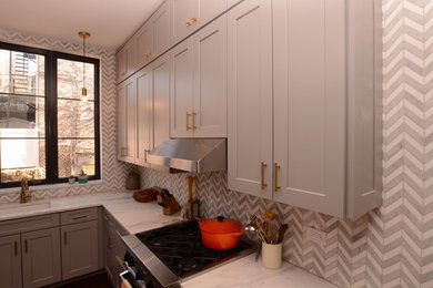 Example of a mid-sized transitional u-shaped dark wood floor enclosed kitchen design in New York with an undermount sink, shaker cabinets, gray cabinets, marble countertops, gray backsplash, porcelain backsplash and stainless steel appliances