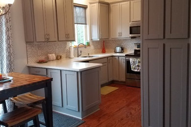 Minimalist eat-in kitchen photo in Milwaukee with shaker cabinets, gray cabinets, solid surface countertops, a peninsula and white countertops