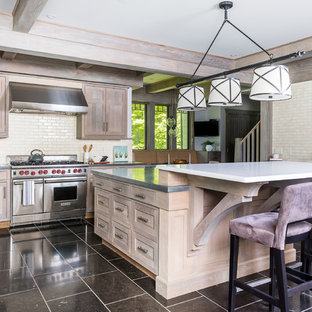 Photo of a large country l-shaped eat-in kitchen in Boston with a double-bowl sink, beaded inset cabinets, beige cabinets, concrete benchtops, beige splashback, ceramic splashback, stainless steel appliances, marble floors, with island, black floor and grey benchtop.