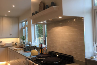 Large country u-shaped kitchen/diner in Devon with a submerged sink, shaker cabinets, white cabinets, quartz worktops, grey splashback, ceramic splashback, stainless steel appliances, vinyl flooring, an island, multi-coloured floors, grey worktops and exposed beams.