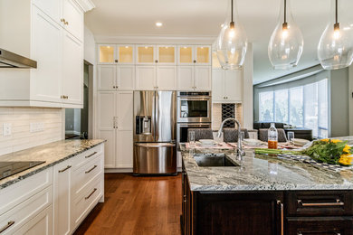 Large transitional u-shaped dark wood floor and brown floor enclosed kitchen photo in Vancouver with a double-bowl sink, shaker cabinets, white cabinets, quartzite countertops, white backsplash, subway tile backsplash, stainless steel appliances, an island and gray countertops