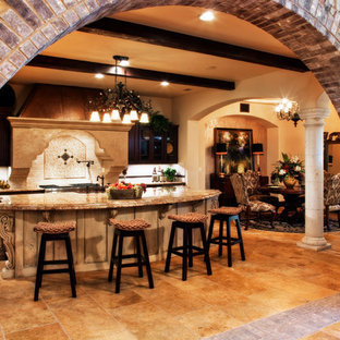 Design ideas for a large mediterranean l-shaped open plan kitchen in Austin with a farmhouse sink, raised-panel cabinets, dark wood cabinets, granite benchtops, beige splashback, ceramic splashback, stainless steel appliances, ceramic floors, with island and beige floor.