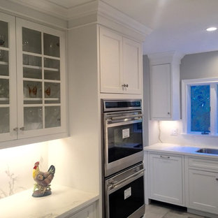 Photo of a mid-sized transitional l-shaped kitchen pantry in New York with an undermount sink, flat-panel cabinets, white cabinets, recycled glass benchtops, white splashback, glass sheet splashback, panelled appliances, dark hardwood floors and no island.