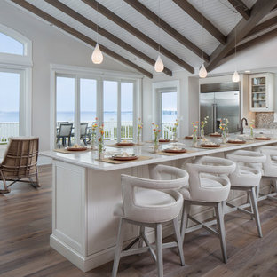 Idee per una grande cucina stile marino con ante bianche, top in quarzite, paraspruzzi multicolore, elettrodomestici in acciaio inossidabile, isola, ante di vetro, pavimento in legno massello medio, lavello sottopiano, paraspruzzi con piastrelle a mosaico e pavimento marrone