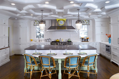 Example of a transitional medium tone wood floor kitchen design in New York with white cabinets, marble countertops, white backsplash, ceramic backsplash, stainless steel appliances and an island