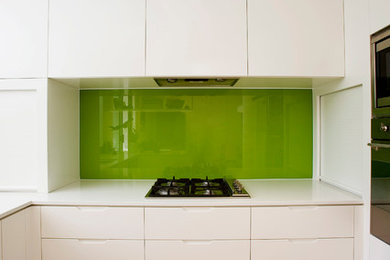 Modelo de cocina minimalista con encimera de cuarzo compacto, salpicadero gris y salpicadero de vidrio templado