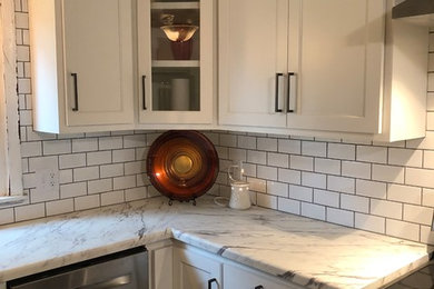 Klassisk inredning av ett avskilt, mellanstort grå grått u-kök, med en undermonterad diskho, skåp i shakerstil, vita skåp, marmorbänkskiva, vitt stänkskydd, stänkskydd i tunnelbanekakel, rostfria vitvaror, mörkt trägolv, en halv köksö och brunt golv