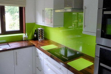 Réalisation d'une cuisine avec une crédence verte et une crédence en feuille de verre.