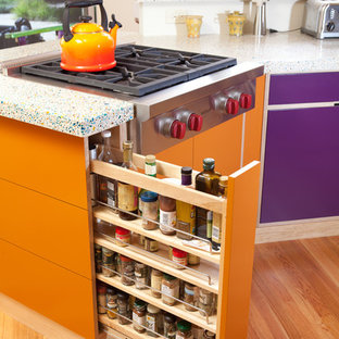 Mid-sized eclectic u-shaped eat-in kitchen in San Luis Obispo with flat-panel cabinets, stainless steel appliances, an undermount sink, light wood cabinets, blue splashback, subway tile splashback, medium hardwood floors, a peninsula, brown floor, recycled glass benchtops and multi-coloured benchtop.