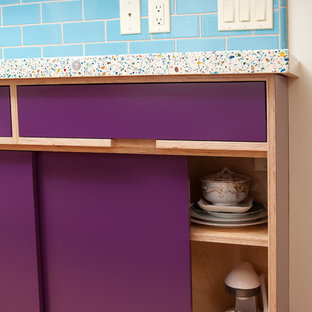 This is an example of a mid-sized eclectic u-shaped eat-in kitchen in San Luis Obispo with an undermount sink, flat-panel cabinets, light wood cabinets, blue splashback, subway tile splashback, stainless steel appliances, medium hardwood floors, a peninsula, brown floor, recycled glass benchtops and multi-coloured benchtop.
