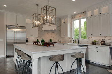 Open concept kitchen - large transitional l-shaped dark wood floor and brown floor open concept kitchen idea in Nashville with a farmhouse sink, shaker cabinets, white cabinets, marble countertops, white backsplash, brick backsplash, stainless steel appliances, an island and white countertops