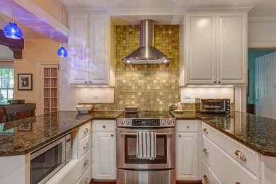 Foto på ett mellanstort vintage kök, med en undermonterad diskho, luckor med upphöjd panel, vita skåp, granitbänkskiva, flerfärgad stänkskydd, stänkskydd i glaskakel, rostfria vitvaror, mellanmörkt trägolv och en halv köksö