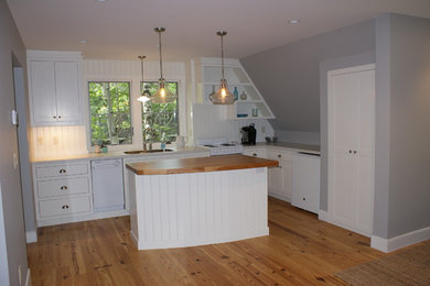 Example of a small beach style l-shaped light wood floor open concept kitchen design in Minneapolis with an undermount sink, recessed-panel cabinets, white cabinets, laminate countertops, white backsplash, white appliances and an island