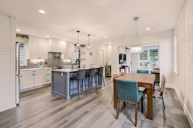 Example of a small trendy l-shaped medium tone wood floor open concept kitchen design in Seattle with an undermount sink, shaker cabinets, white cabinets, quartz countertops, gray backsplash, ceramic backsplash, stainless steel appliances, an island and white countertops