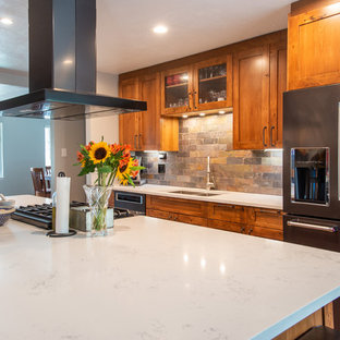This is an example of a large country l-shaped eat-in kitchen in Denver with an undermount sink, shaker cabinets, brown cabinets, quartz benchtops, multi-coloured splashback, slate splashback, stainless steel appliances, medium hardwood floors, with island, brown floor and white benchtop.