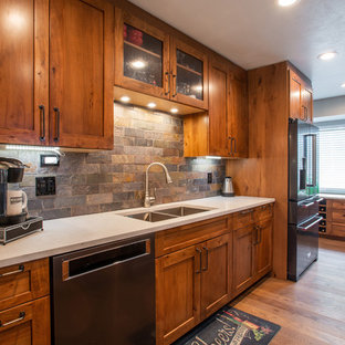 Large country l-shaped eat-in kitchen in Denver with an undermount sink, shaker cabinets, brown cabinets, quartz benchtops, multi-coloured splashback, slate splashback, stainless steel appliances, medium hardwood floors, with island, brown floor and white benchtop.
