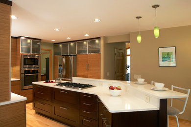 Eat-in kitchen - contemporary l-shaped eat-in kitchen idea in Milwaukee with an undermount sink, flat-panel cabinets, medium tone wood cabinets, glass tile backsplash and stainless steel appliances