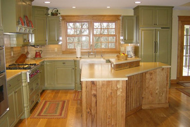 Example of a large cottage l-shaped medium tone wood floor eat-in kitchen design in Milwaukee with a farmhouse sink, green cabinets, beige backsplash, an island, raised-panel cabinets and paneled appliances