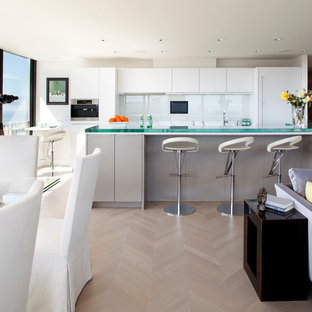Immagine di una cucina ad ambiente unico minimal con ante lisce, paraspruzzi con lastra di vetro, ante bianche, paraspruzzi bianco, top in vetro e elettrodomestici da incasso