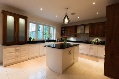 Photo of a large contemporary u-shaped kitchen pantry in Kent with a belfast sink, shaker cabinets, dark wood cabinets, granite worktops, stainless steel appliances, porcelain flooring and an island.