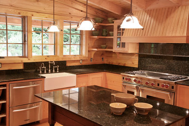Inspiration for a country light wood floor kitchen remodel in Seattle with a farmhouse sink, shaker cabinets, medium tone wood cabinets, quartzite countertops, black backsplash, stone slab backsplash and stainless steel appliances