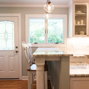 Small transitional enclosed kitchen inspiration - Example of a small transitional u-shaped medium tone wood floor enclosed kitchen design in Milwaukee with a farmhouse sink, shaker cabinets, white cabinets, granite countertops, white backsplash, subway tile backsplash, stainless steel appliances and a peninsula