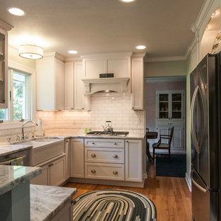 Small transitional enclosed kitchen remodeling - Inspiration for a small transitional u-shaped medium tone wood floor enclosed kitchen remodel in Milwaukee with a farmhouse sink, shaker cabinets, white cabinets, granite countertops, white backsplash, subway tile backsplash, stainless steel appliances and a peninsula