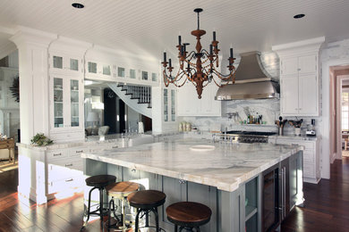 Transitional l-shaped eat-in kitchen photo in New York with a farmhouse sink, shaker cabinets, white cabinets, marble countertops, white backsplash, stone slab backsplash and stainless steel appliances