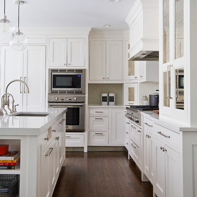 Kitchen - mid-sized transitional l-shaped dark wood floor kitchen idea in New York with a farmhouse sink, white cabinets, quartz countertops, gray backsplash, ceramic backsplash, paneled appliances, an island and recessed-panel cabinets