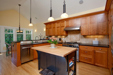 Example of an arts and crafts eat-in kitchen design in Seattle with stainless steel appliances, wood countertops, a single-bowl sink, shaker cabinets, medium tone wood cabinets, beige backsplash and travertine backsplash