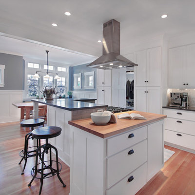 Eat-in kitchen - mid-sized craftsman l-shaped medium tone wood floor and brown floor eat-in kitchen idea in Seattle with wood countertops, shaker cabinets, white cabinets, white backsplash, glass tile backsplash, an undermount sink, stainless steel appliances, an island and gray countertops