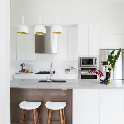 Mid-sized danish galley light wood floor open concept kitchen photo in Toronto with an undermount sink, flat-panel cabinets, white cabinets, quartzite countertops, white backsplash, stainless steel appliances and an island