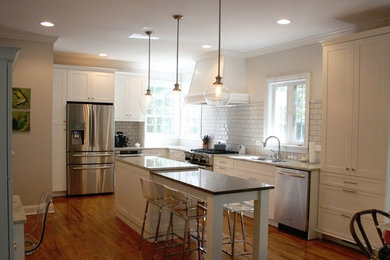 Inspiration for a mid-sized transitional l-shaped medium tone wood floor open concept kitchen remodel in Birmingham with an undermount sink, recessed-panel cabinets, white cabinets, granite countertops, white backsplash, subway tile backsplash, stainless steel appliances and an island
