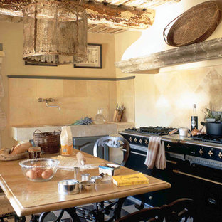 This is an example of a mid-sized mediterranean single-wall eat-in kitchen in New York with an integrated sink, limestone benchtops, brown splashback, travertine splashback, black appliances, porcelain floors, no island and multi-coloured floor.