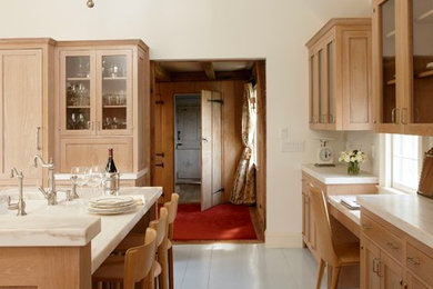 Ejemplo de cocina campestre con armarios tipo vitrina, puertas de armario de madera clara, encimera de mármol, suelo de madera clara y una isla