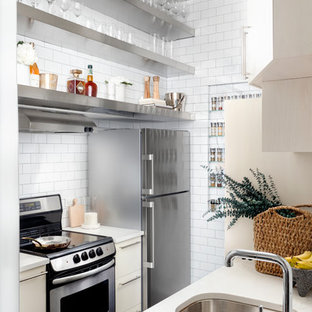 Immagine di una piccola cucina parallela design con lavello sottopiano, nessun'anta, ante in acciaio inossidabile, paraspruzzi bianco, paraspruzzi con piastrelle diamantate e pavimento nero