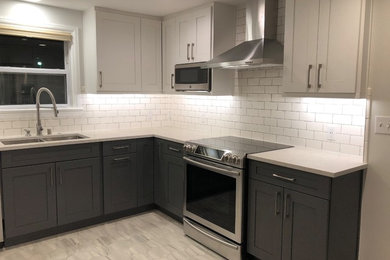 Enclosed kitchen - mid-sized contemporary u-shaped porcelain tile and gray floor enclosed kitchen idea in Seattle with an undermount sink, recessed-panel cabinets, gray cabinets, quartz countertops, white backsplash, ceramic backsplash, stainless steel appliances, no island and gray countertops