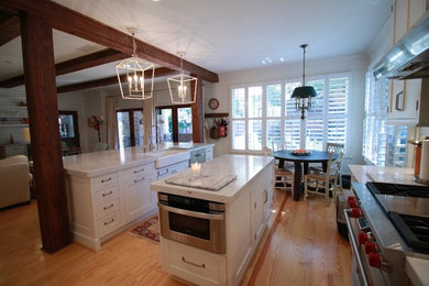 Exempel på ett stort klassiskt vit vitt kök, med en rustik diskho, skåp i shakerstil, vita skåp, bänkskiva i kvartsit, vitt stänkskydd, stänkskydd i tunnelbanekakel, rostfria vitvaror, ljust trägolv, flera köksöar och brunt golv