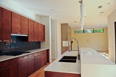 Exempel på ett stort modernt kök, med en dubbel diskho, släta luckor, skåp i mellenmörkt trä, stänkskydd i tunnelbanekakel, rostfria vitvaror, mellanmörkt trägolv, en köksö, brunt golv och blått stänkskydd