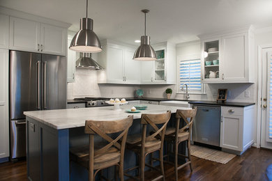 Inspiration for a mid-sized transitional l-shaped dark wood floor enclosed kitchen remodel in Atlanta with a farmhouse sink, shaker cabinets, white cabinets, marble countertops, white backsplash, ceramic backsplash, stainless steel appliances and an island