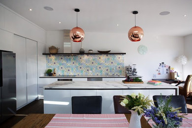 Photo of a medium sized contemporary l-shaped open plan kitchen in Auckland with a single-bowl sink, white cabinets, marble worktops, multi-coloured splashback, ceramic splashback, stainless steel appliances, dark hardwood flooring and an island.