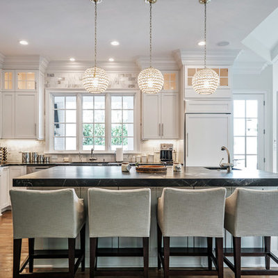 Example of a mid-sized classic l-shaped medium tone wood floor open concept kitchen design in Other with an undermount sink, shaker cabinets, white cabinets, marble countertops, white backsplash, marble backsplash, paneled appliances and an island