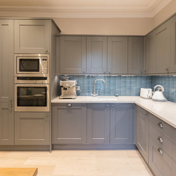 Grey shaker-style L-shaped kitchen with blue tiles